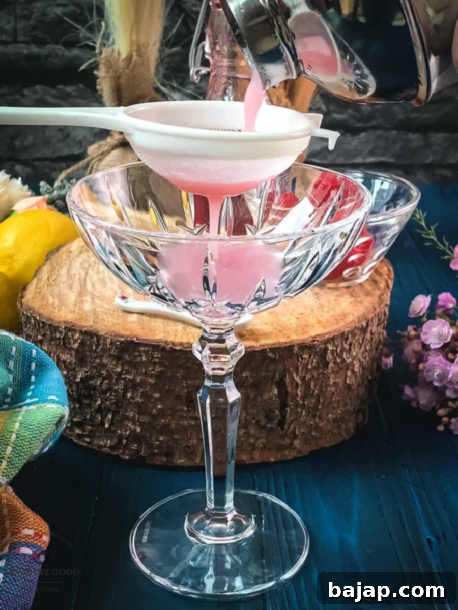 Fine strain the Clover Club cocktail into a chilled glass before serving to achieve a smooth, frothy texture.