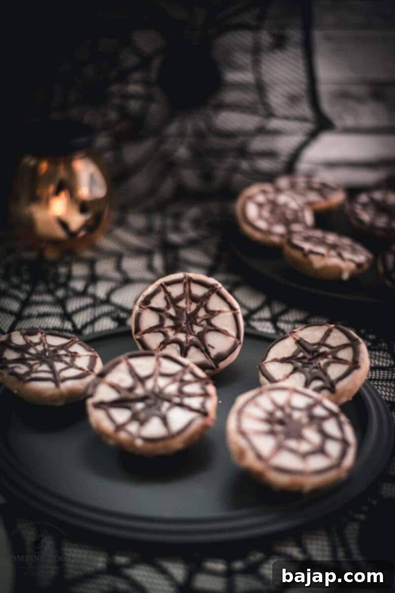 Spooky Sweet Spiderweb Treats 11 Hauntingly delicious spiderweb cookies, placed on black plate on spiderweb ground.