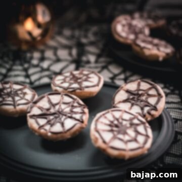 Hauntingly delicious spiderweb cookies, placed on black plate on spiderweb ground.
