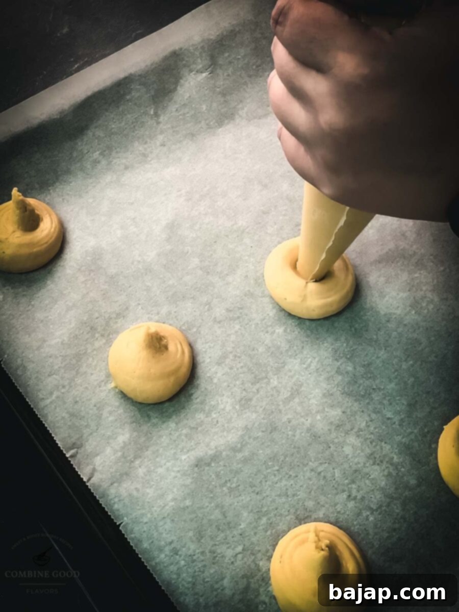 Pipe 1.5-inch (4cm) cookies onto the trays. Shows raw vanilla custard cookie dough on parchment paper.