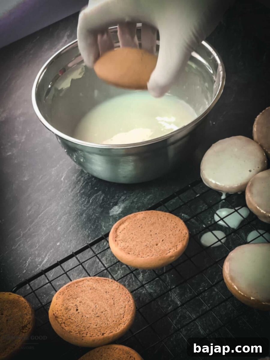 Dip the flat side of the cookies into the icing, preparing for the Halloween spiderweb design.
