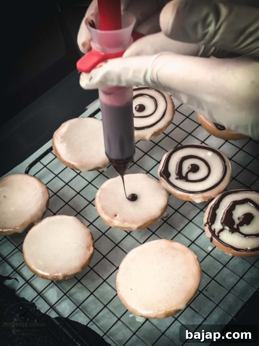 Drawing a chocolate dot in the middle of the cookie glaze, using a cake decorating pen, for a Halloween spiderweb.