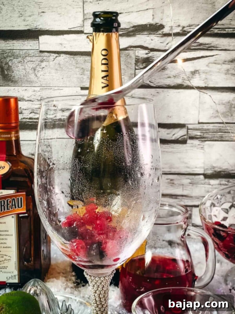 Spooning red and black currants and cranberries into a wine glass as the first layer of the Prosecco Cosmo.