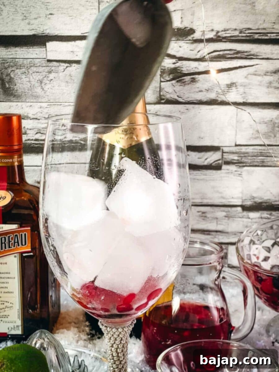 Adding cubed ice to a wine glass that already contains frozen fruit for a Prosecco Cosmo.