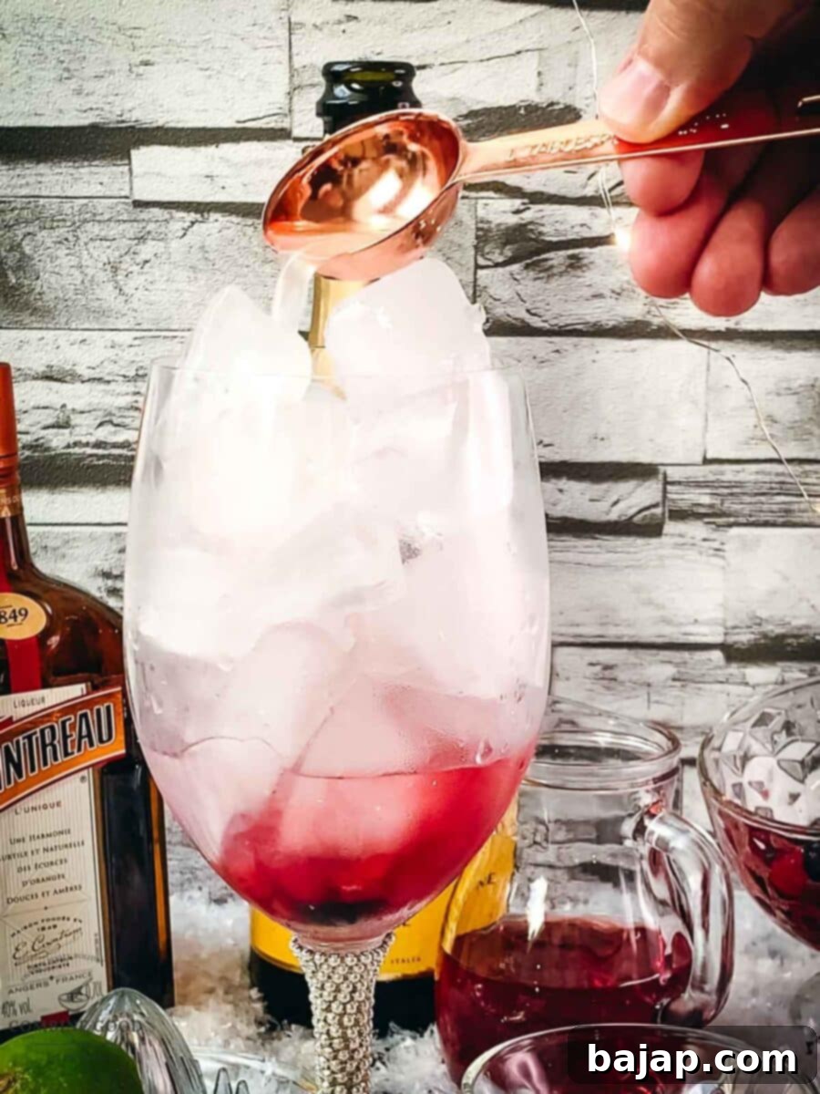 Squeezing and adding freshly squeezed lime juice into the Prosecco Cosmo cocktail with a measuring spoon.