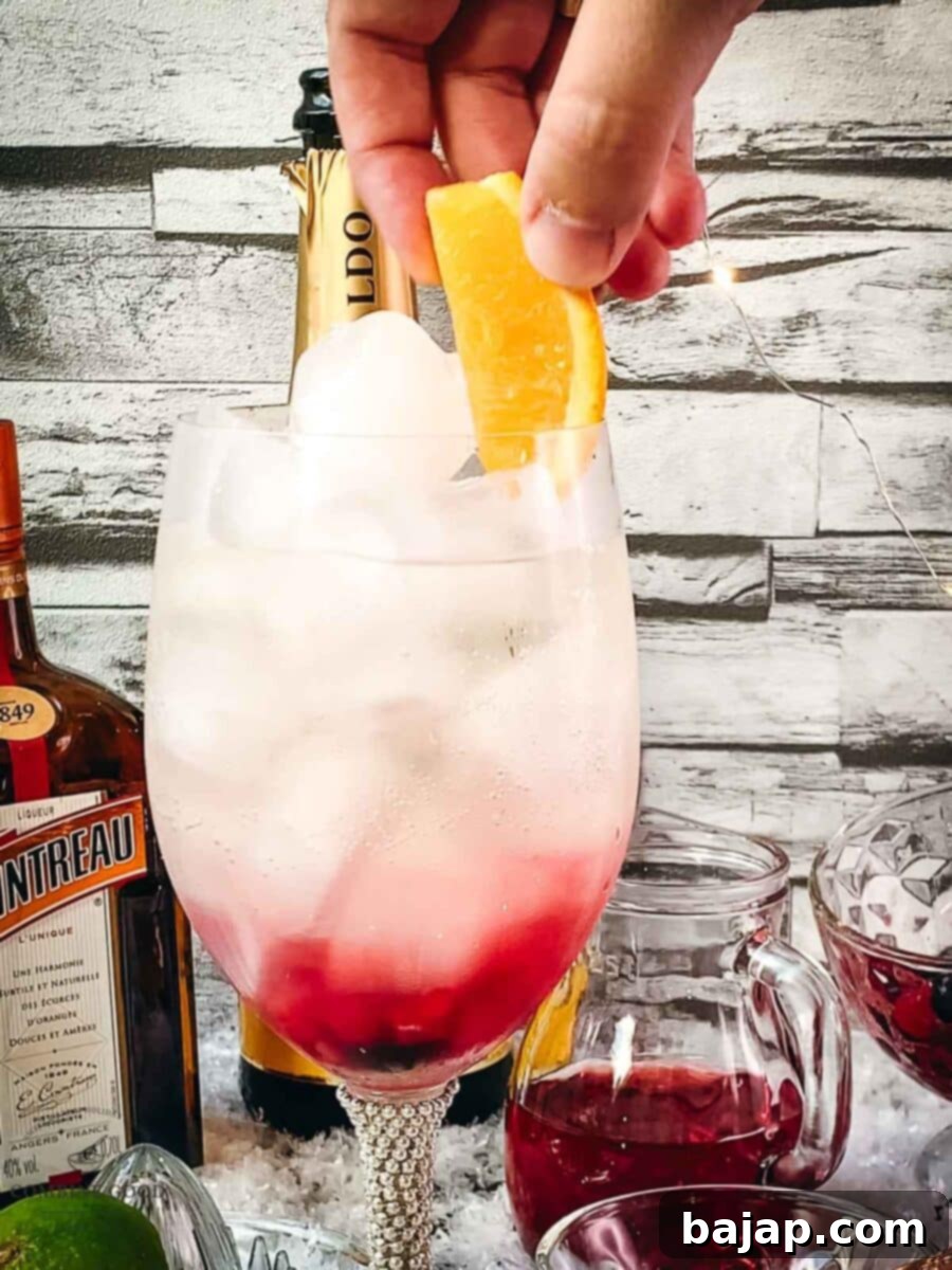 Placing an orange slice as a garnish on the Prosecco Cosmo cocktail.