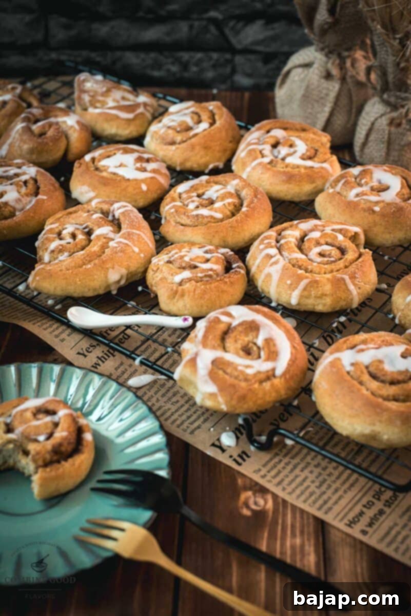 Yummy mini cinnamon rolls, drizzled with homemade sugar icing, placed on cooling rack.