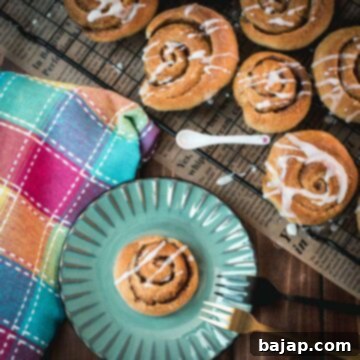 Yummy mini cinnamon rolls, drizzled with homemade sugar icing, placed on teal colored plate.