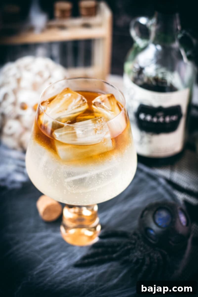 Gorgeous layered kraken ginger beer cocktail with spooky decoration and dark rum floating on top.