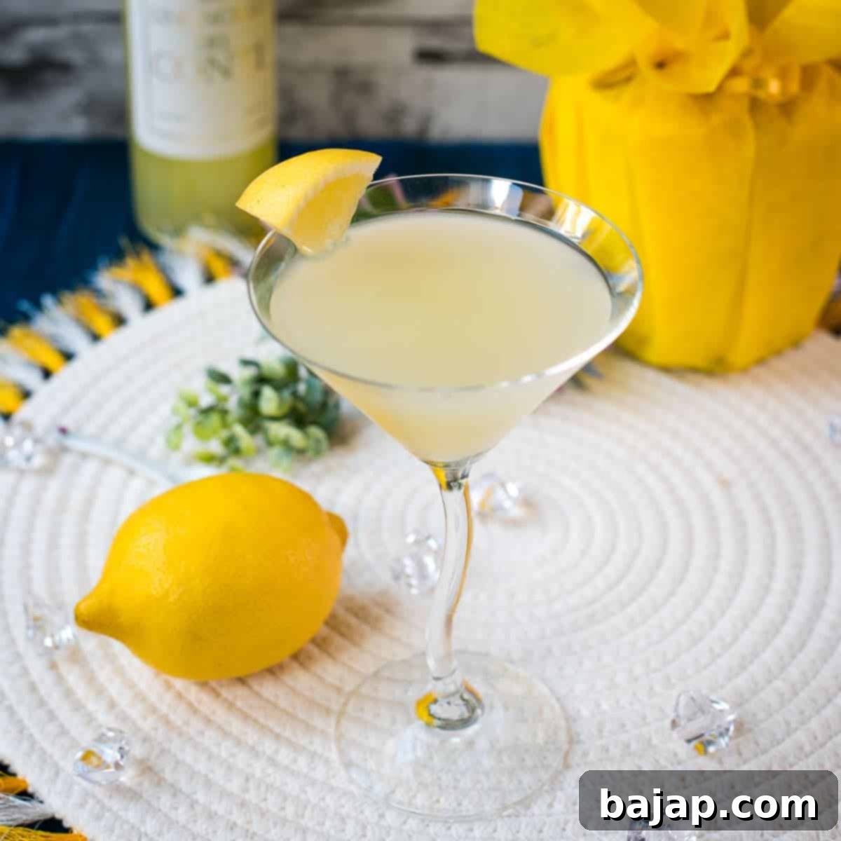 Gorgeous cocktail glass filled with a vibrant limoncello martini, garnished with a lemon wedge.