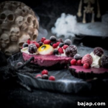 Hauntingly delicious mini Oreo tarts filled with a berry mix ganache, garnished with a creepy gummy eye, frozen berries and whipped cream. Placed on a black plate covered with spider webs.