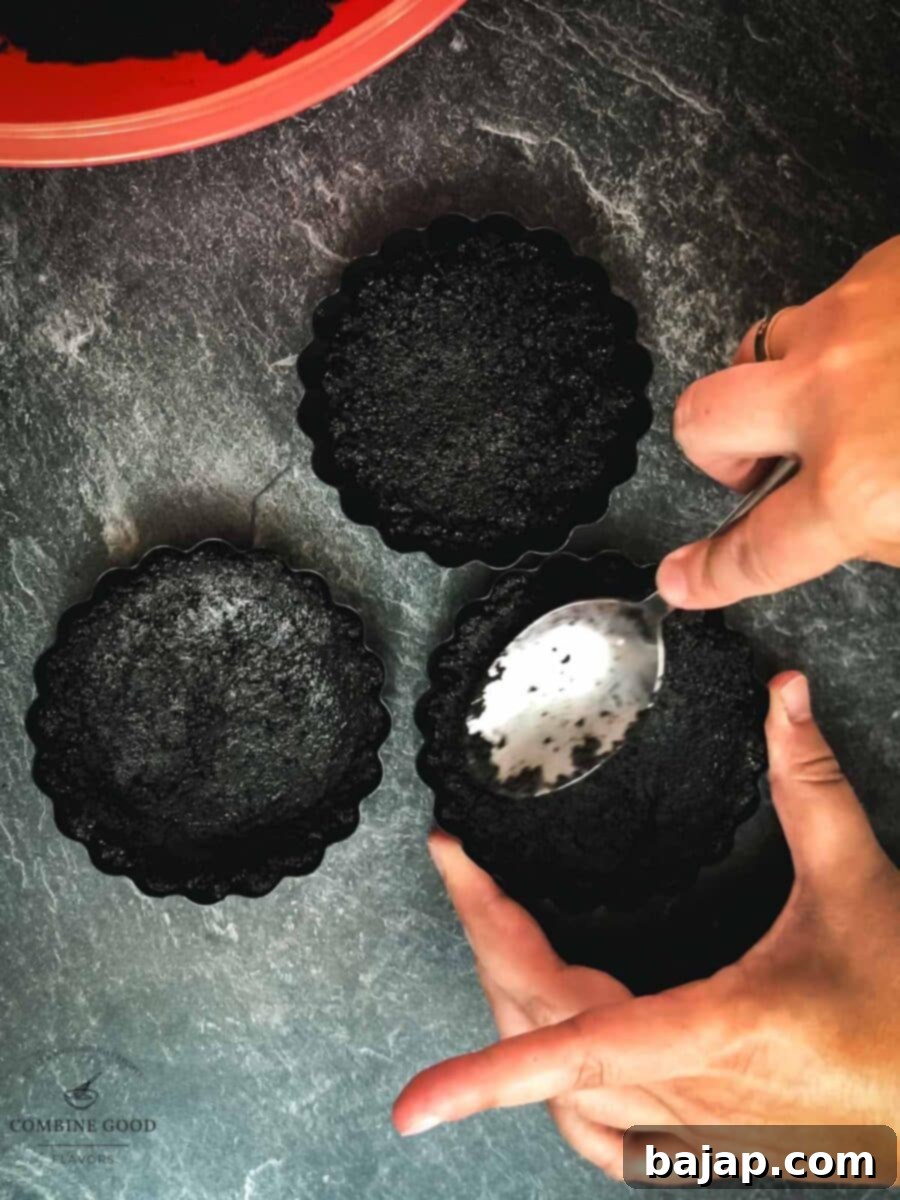Press the buttery Oreo mix into the mini tart tins.