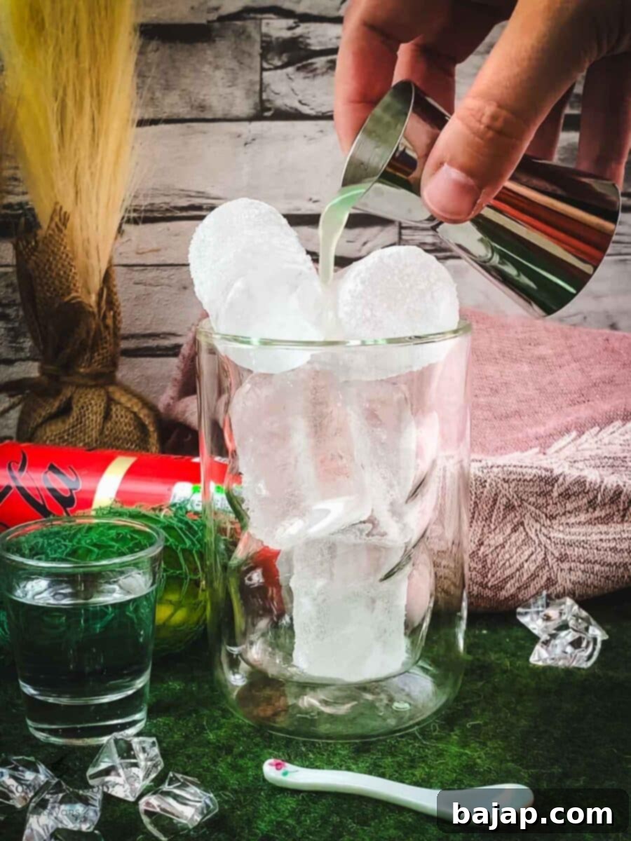 Pouring fresh lime juice into a glass filled with ice for a Cuba Libre.