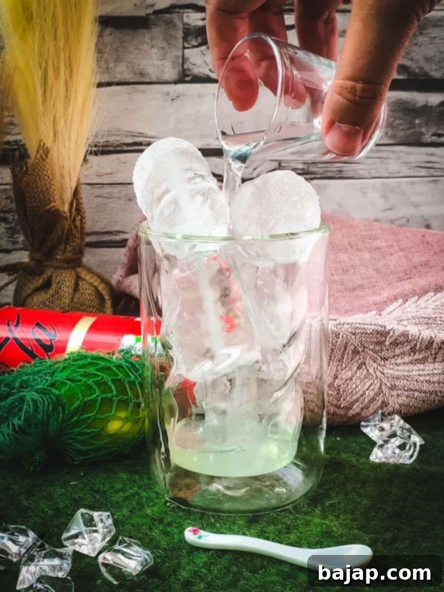 Adding rum to the glass over the ice and lime juice mixture.