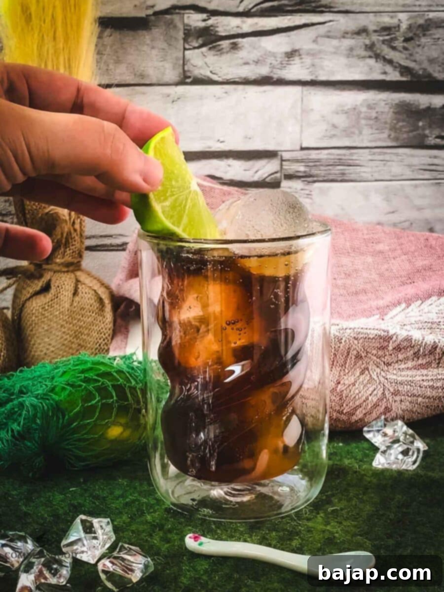 Garnishing the finished Cuba Libre cocktail with a fresh lime wedge.
