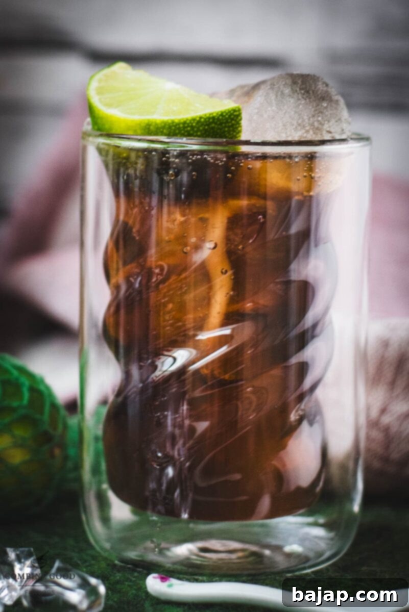 Twisted glass filled with a delicious Cuba Libre cocktail, placed on green felt mat.