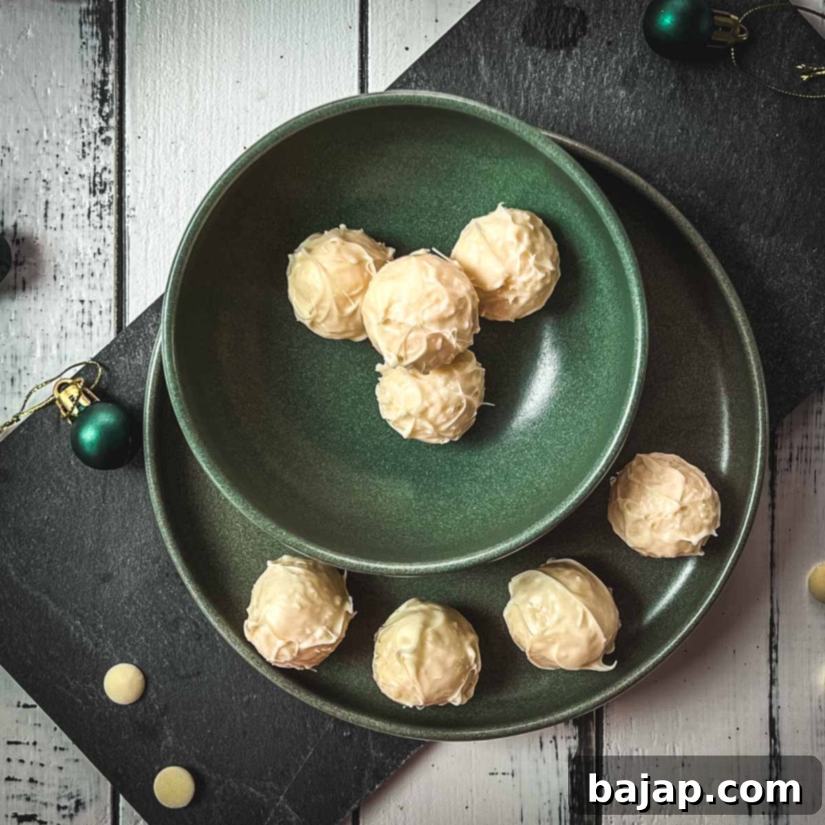 Charming coconut truffles in green bowl next to Christmas decoration.