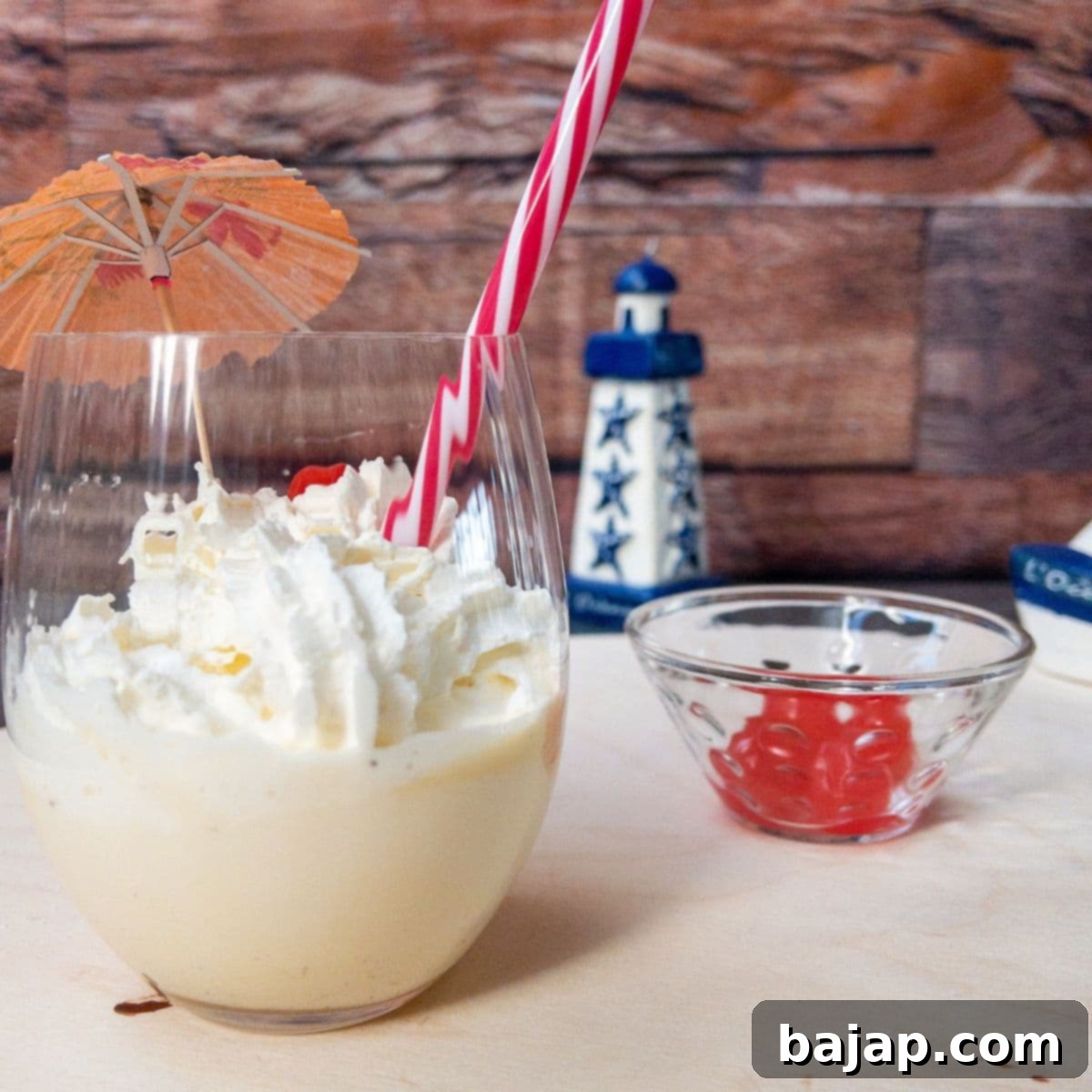 Glass with homemade eggnog milkshake, topped with whipped cream and a yummy cocktail cherry on top.