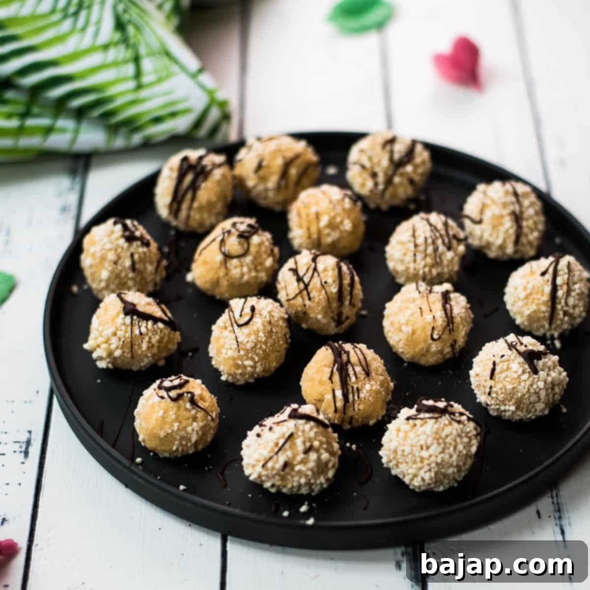 Gorgeous mascarpone eggnog cookies, rolled in ladyfinger crumbs and drizzled with chocolate sauce. Placed on black serving plate.