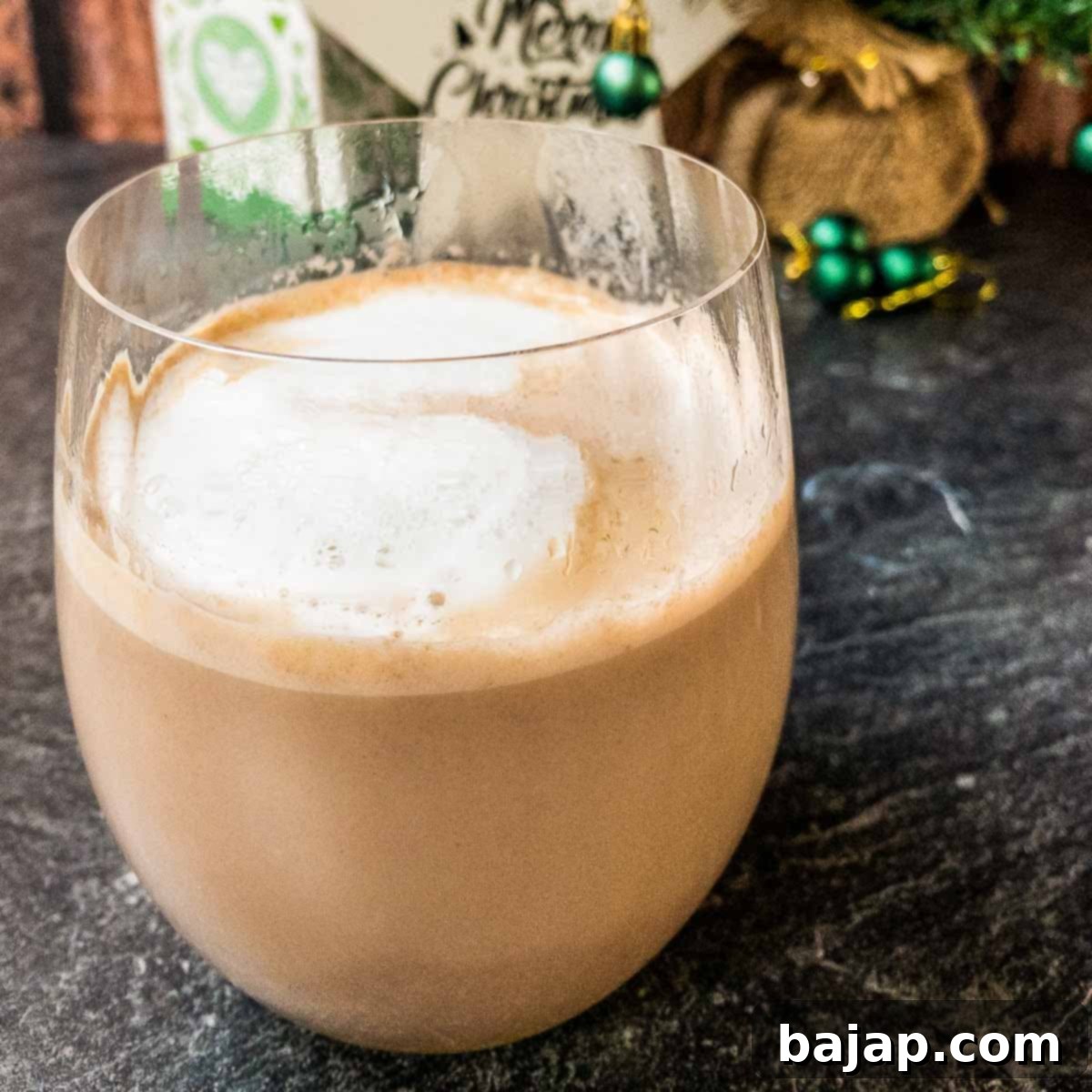 Drinking glass filled with eggnog and hot chocolate with a yummy milk foam on top!