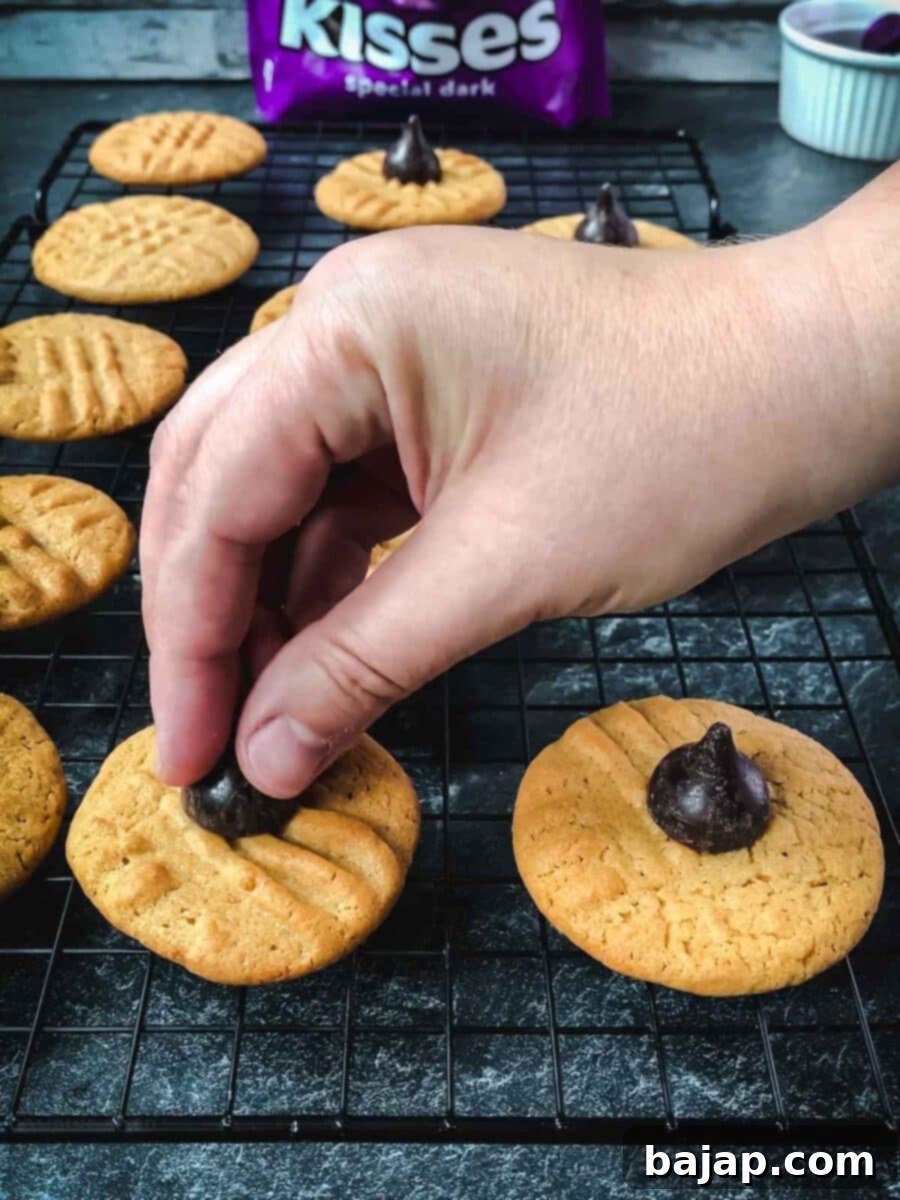 Gently pressing a Hershey's dark chocolate kiss into the center of a warm peanut butter cookie, allowing it to melt slightly.