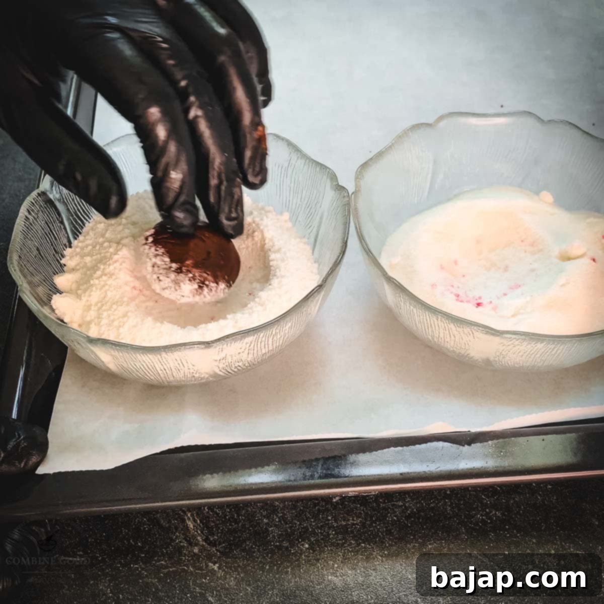 Minty Chocolate Crinkle Delights 15 A gloved hand rolling a chocolate peppermint cookie dough ball in a bowl of powdered sugar.