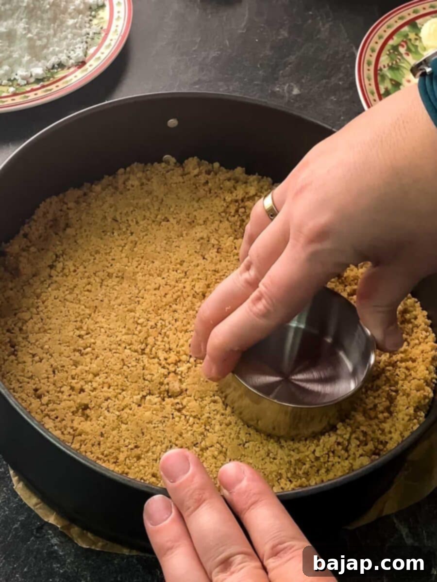 Press the vanilla crescent crumb mixture firmly and evenly into a springform pan to create a sturdy crust for the cheesecake.