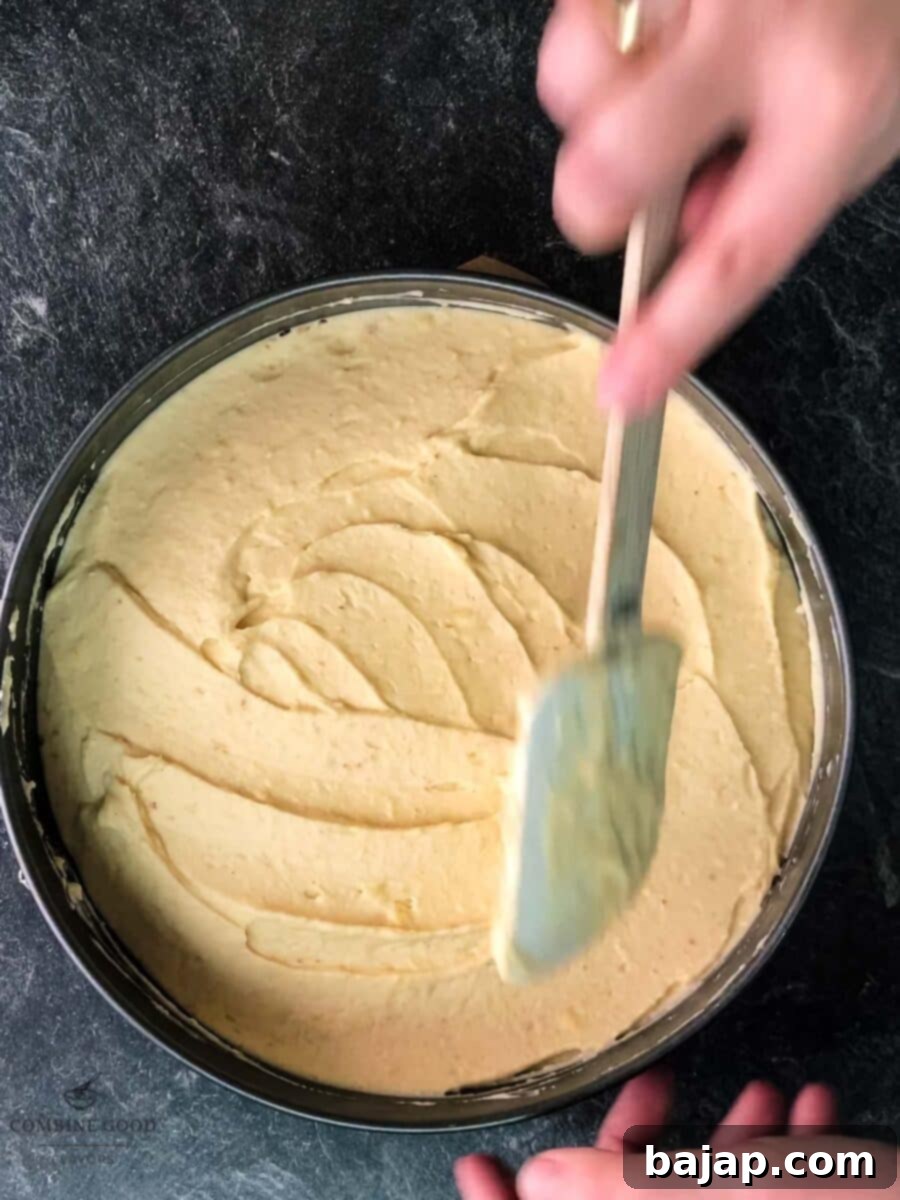 Smoothly spreading the creamy Christmas filling over the chilled vanilla crescent base in a springform pan.