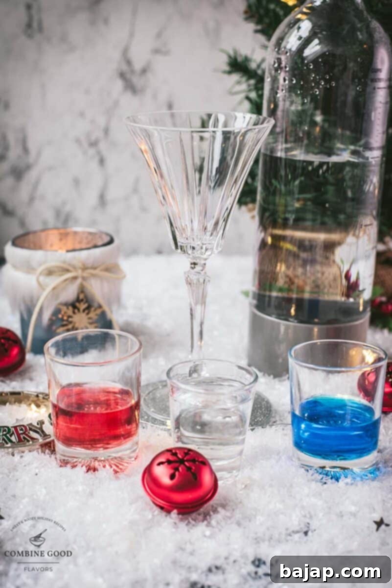 A flat lay of the ingredients for the Blue Christmas Cocktail, including Blue Curaçao, vodka, cranberry juice, and an orange slice.