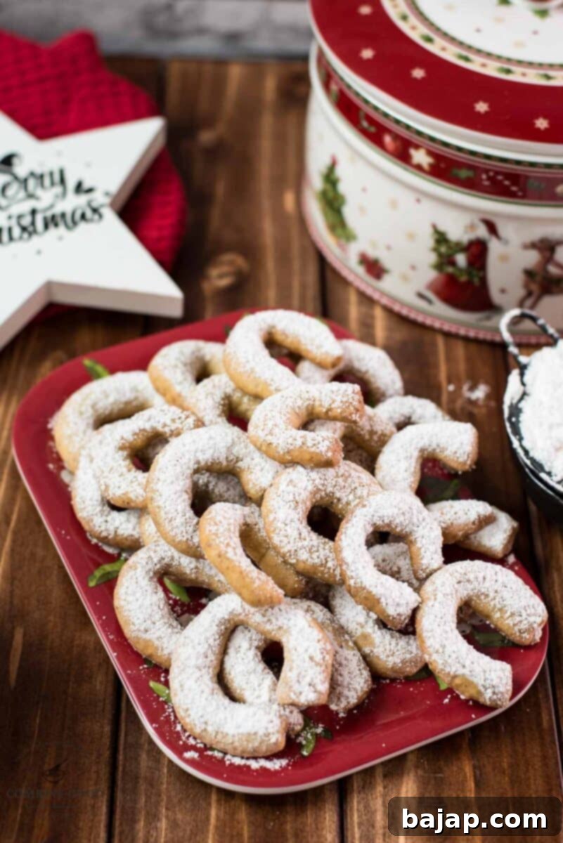 Viennese Vanilla Crescents 2 Delicious traditional Austrian vanilla crescents stacked on christmassy plate, placed next to a Christmass cookie jar.
