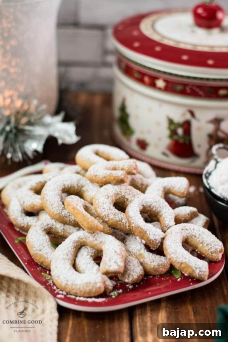 Viennese Vanilla Crescents 12 Delicious traditional Austrian vanilla crescents stacked on christmassy plate, placed next to a Christmass cookie jar.
