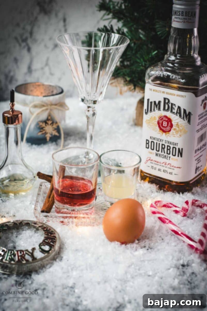 Cranberry cinnamon whiskey sour ingredients: egg white, fresh lemon juice, whiskey, cranberry juice, orange bitters, and a dash of ground cinnamon laid out on a table.