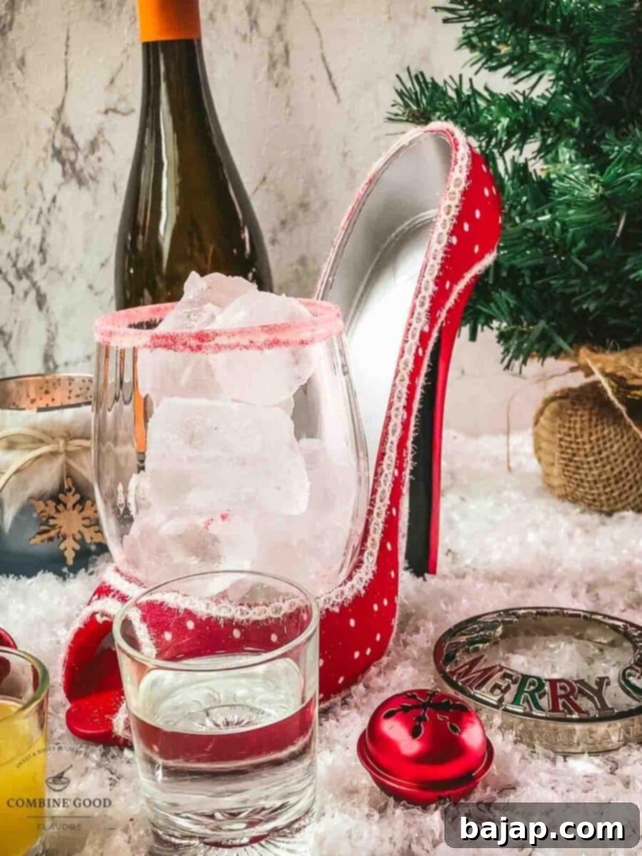 Adding cubed ice to a glass with a pink sugar rim, preparing for a festive Cranberry Vodka Spritzer.
