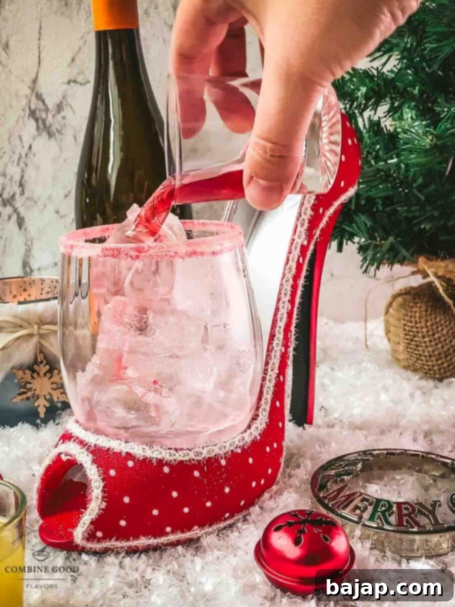 Adding cranberry juice to the glass with vodka and ice for a vibrant Cranberry Vodka Spritzer.