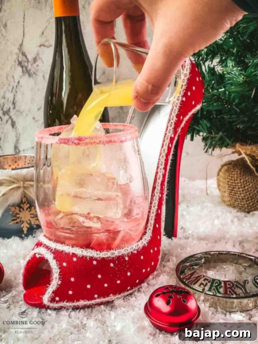 Adding orange juice to the cocktail, creating a colorful mix of liquids for the Cranberry Vodka Spritzer.