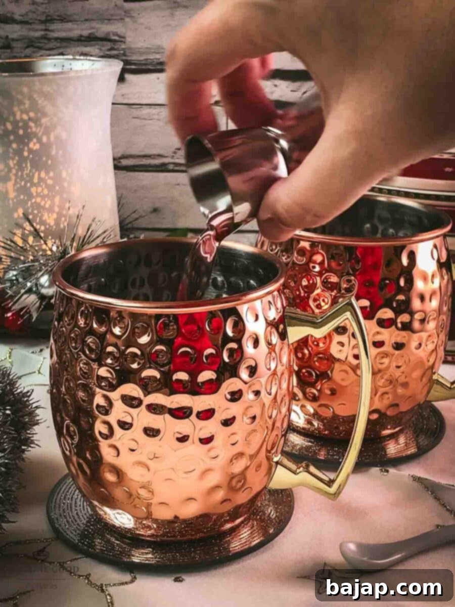 Add cranberry juice to the copper mugs.