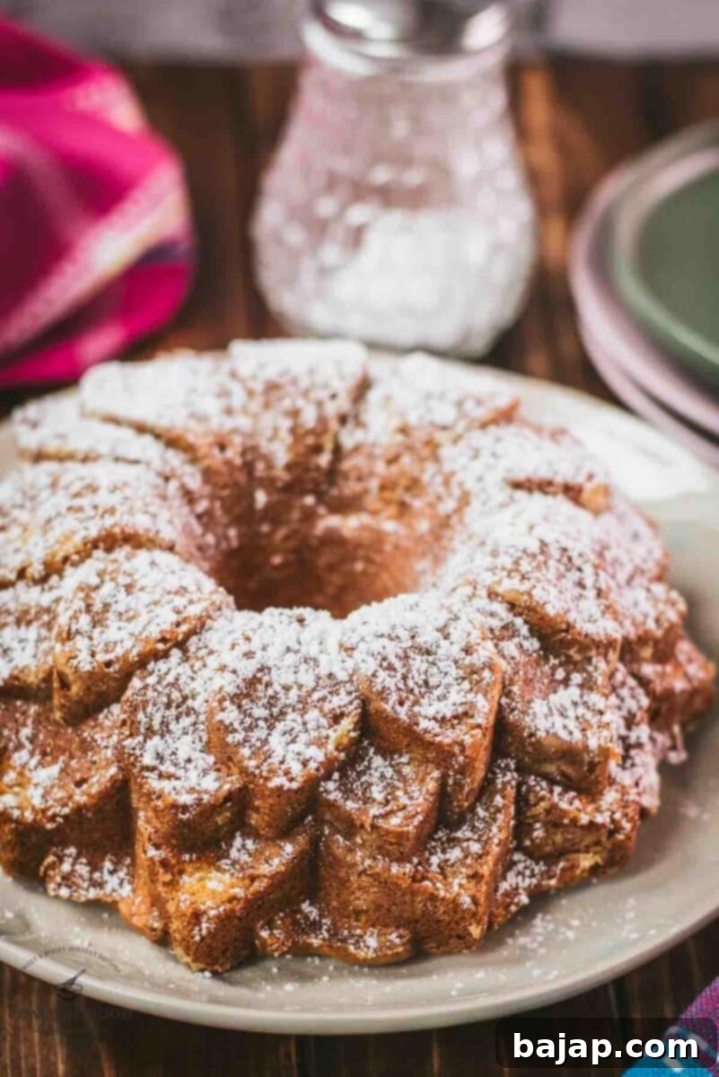 Gorgeous six egg yolk bundt cake, dusted with powdered sugar, and placed on white plate.