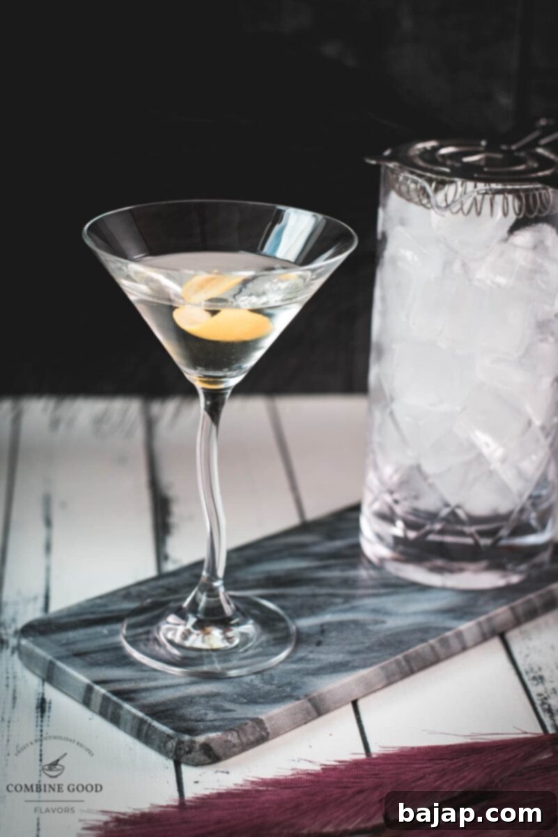 An elegant martini glass, perfectly chilled, resting on a marbled plate. It's garnished with a delicate lemon zest twist, ready to be savored.