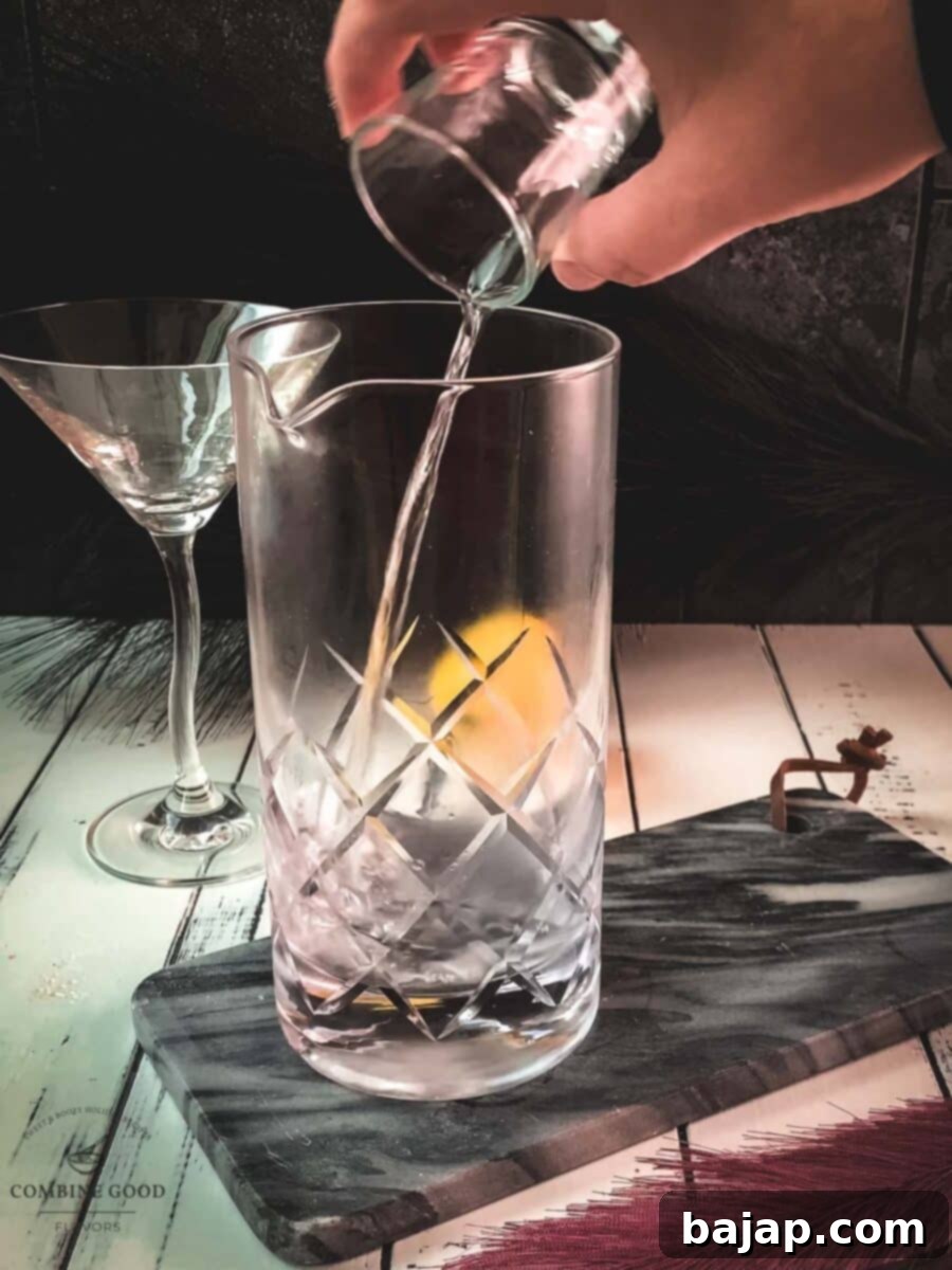 Adding dry vermouth to the gin in a stirring glass, ensuring the perfect ratio for a classic martini.