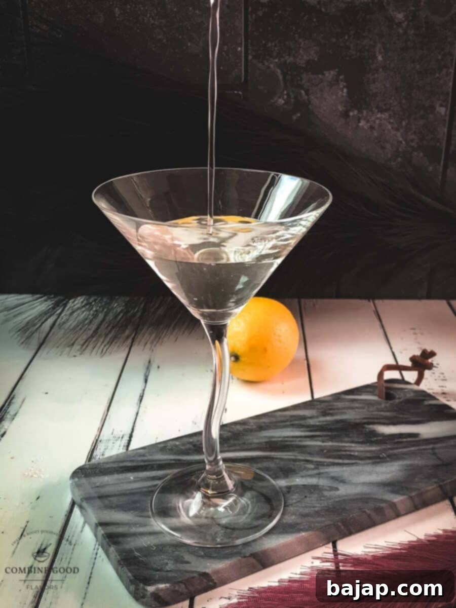 The moment of truth: straining the perfectly chilled martini into an elegant, pre-chilled glass.