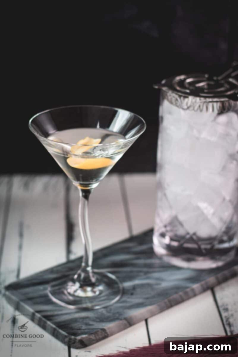 Elegant cocktail glass, placed on marbled plate, and garnished with a lemon zest.