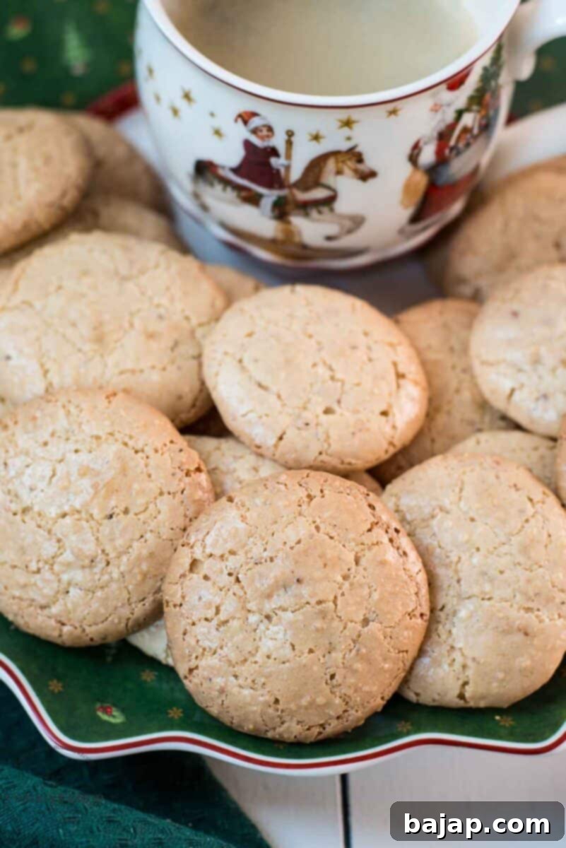 Delicious hazelnut meringue cookies placed on green christmassy plate, next to a coffee mug.