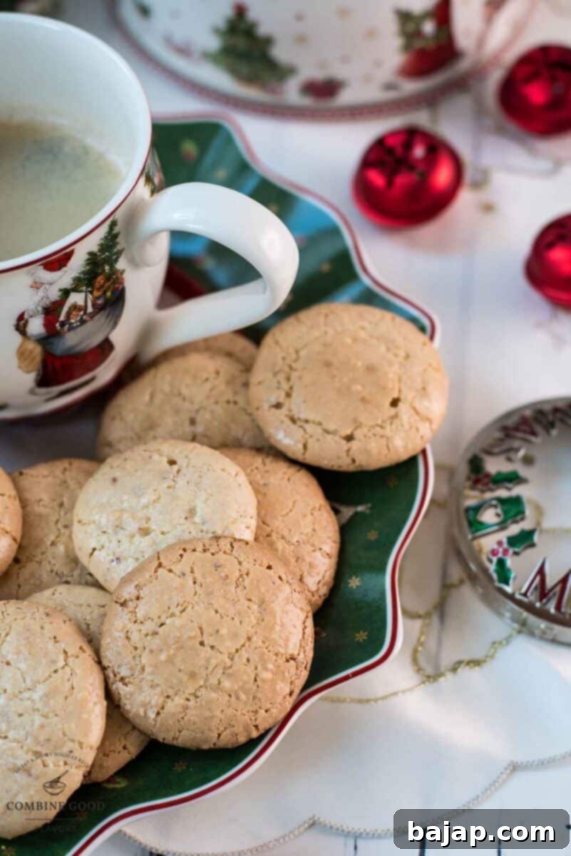 Delicious hazelnut meringue cookies placed on green christmassy plate, next to a coffee mug.
