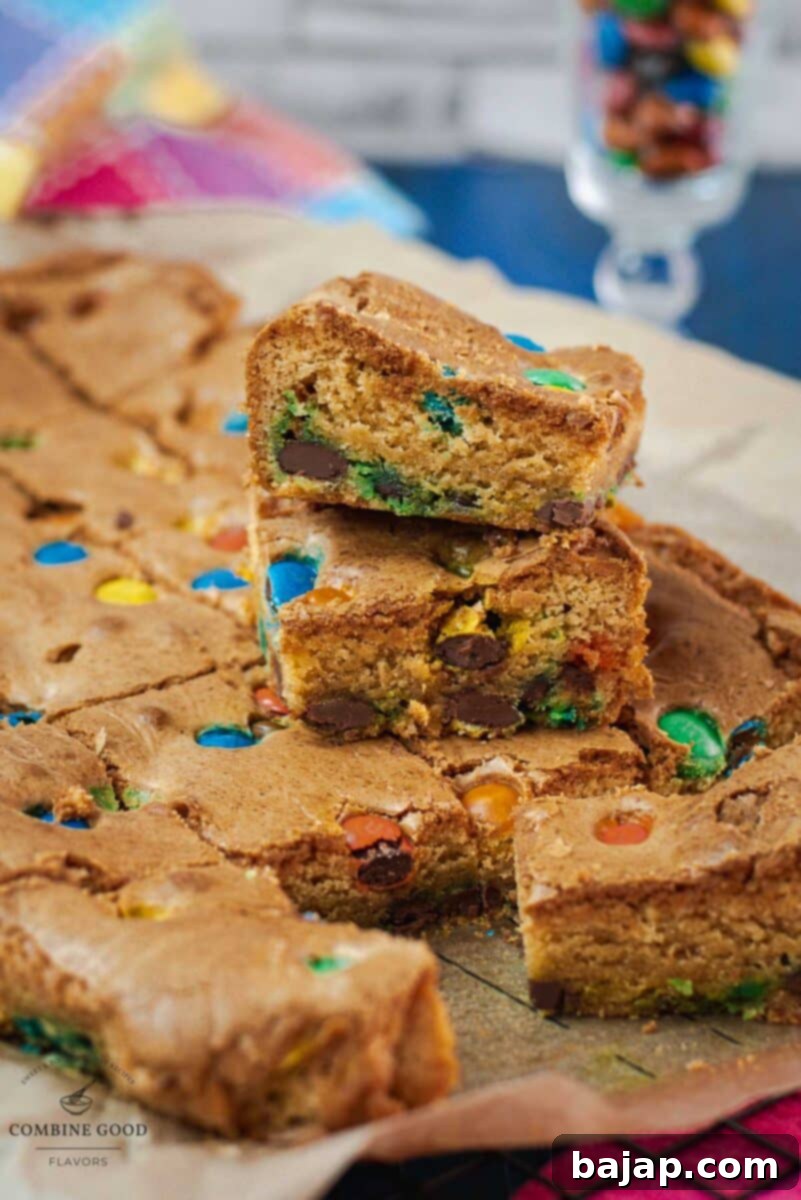 Colorful M and M Cookie Bars 2 Delicious M&M cookie bars on parchment paper, showcasing their vibrant colors and chewy texture.