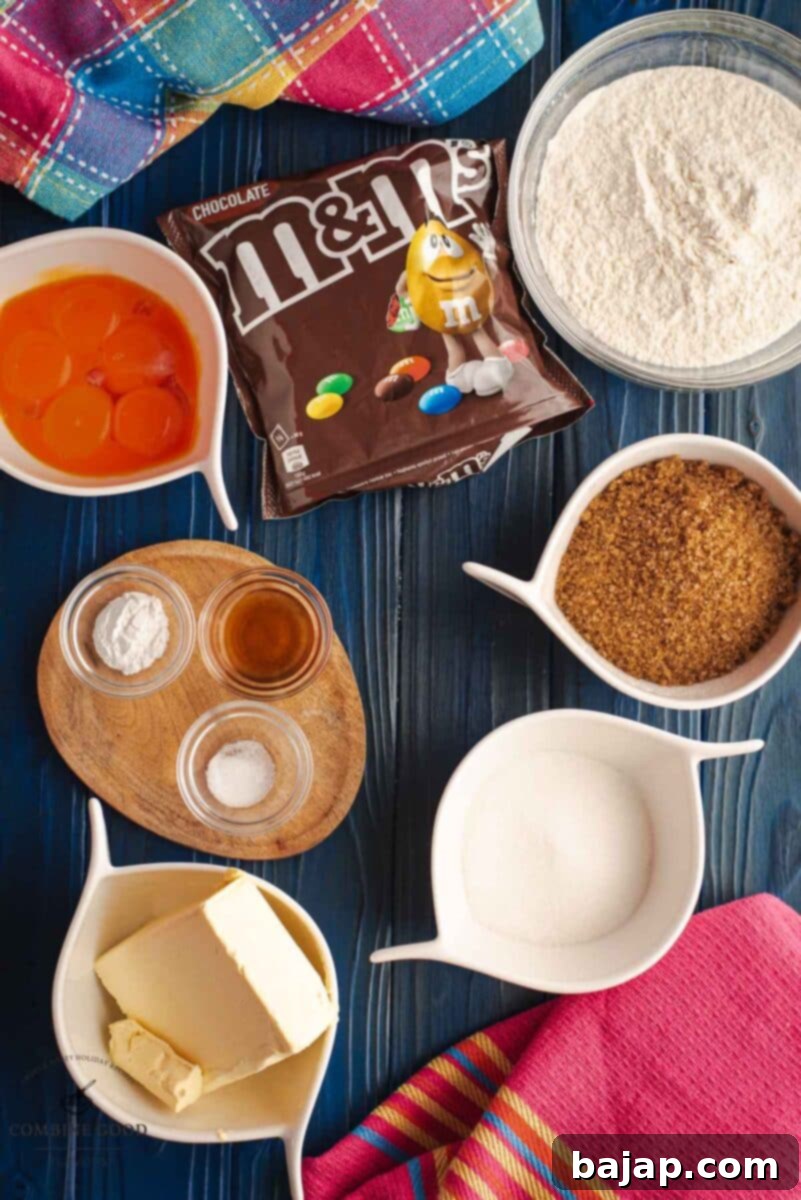 Colorful M and M Cookie Bars 3 Ingredients for M&M cookie bars neatly arranged: brown sugar, granulated sugar, all-purpose flour, six egg yolks, baking powder, salt, melted butter, vanilla extract, and colorful M&Ms.