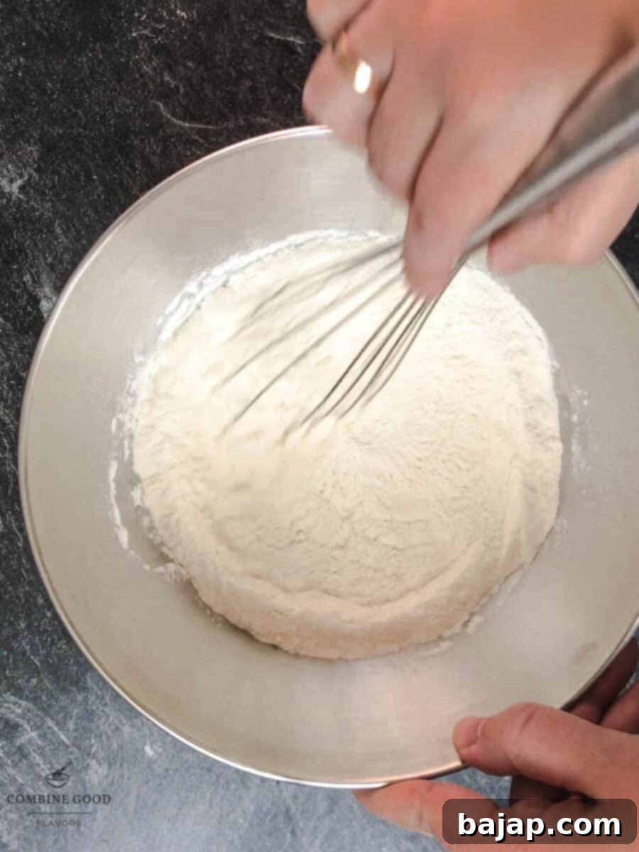 Dry ingredients for M&M cookie bars being whisked in a bowl: flour, baking powder, and salt.