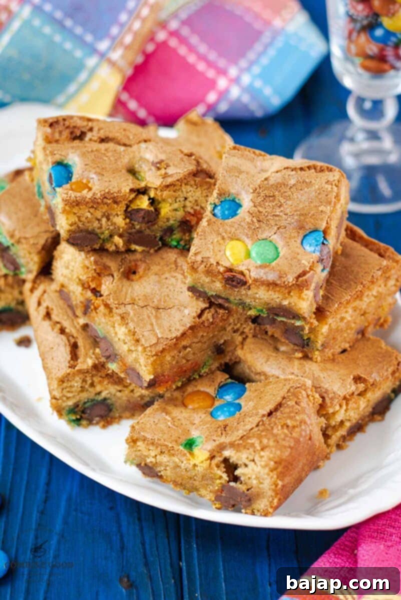 A stack of delicious M&M cookie bars arranged on a white plate, showcasing their inviting appearance.