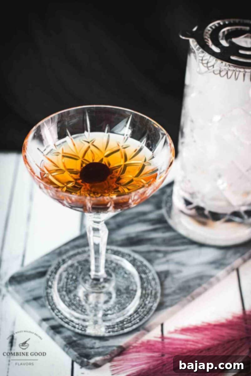 Sophisticated Manhattan cocktail, garnished with a Maraschino cherry, placed on a marbled plate.
