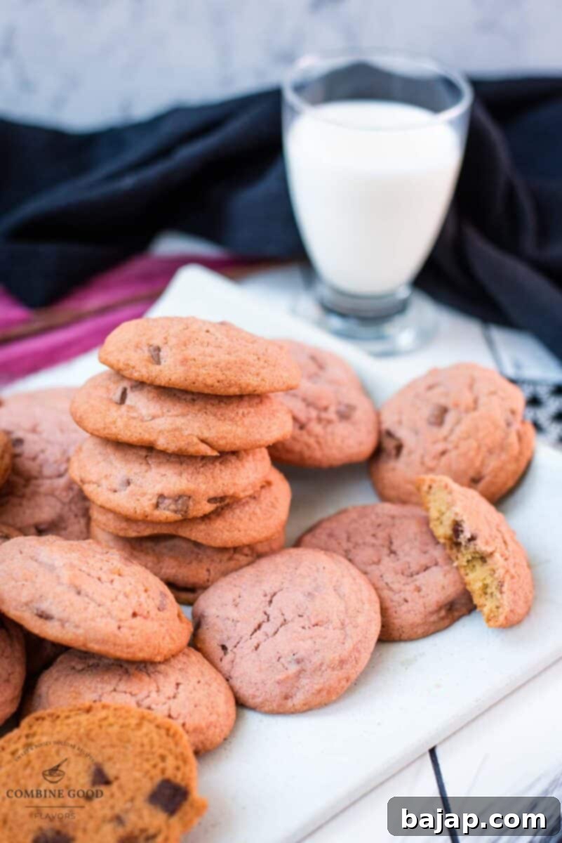 Gorgeous pink cookies on white plate, next to a glass on milk.