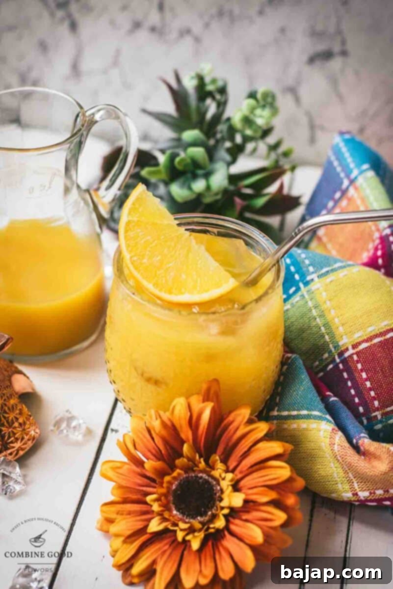 Classic screwdriver cocktail, served in pineapple shaped cocktail glass, placed next to an orange flower.
